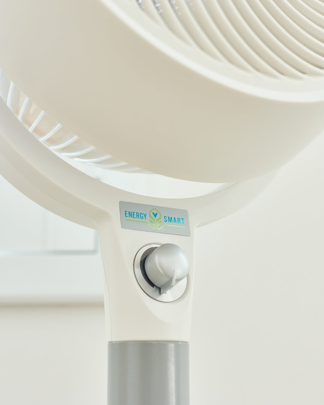 Close-up of a white Vornado 683 Pedestal Air Circulator with a 'Energy Smart' label on a light background