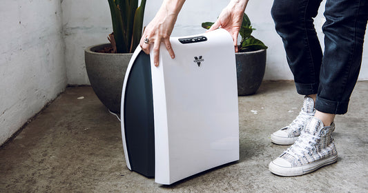 Image of woman wearing sparkly shoes and navy blue pants opening up the front panel of the Vornado AC350 Air Purifier using two hands.