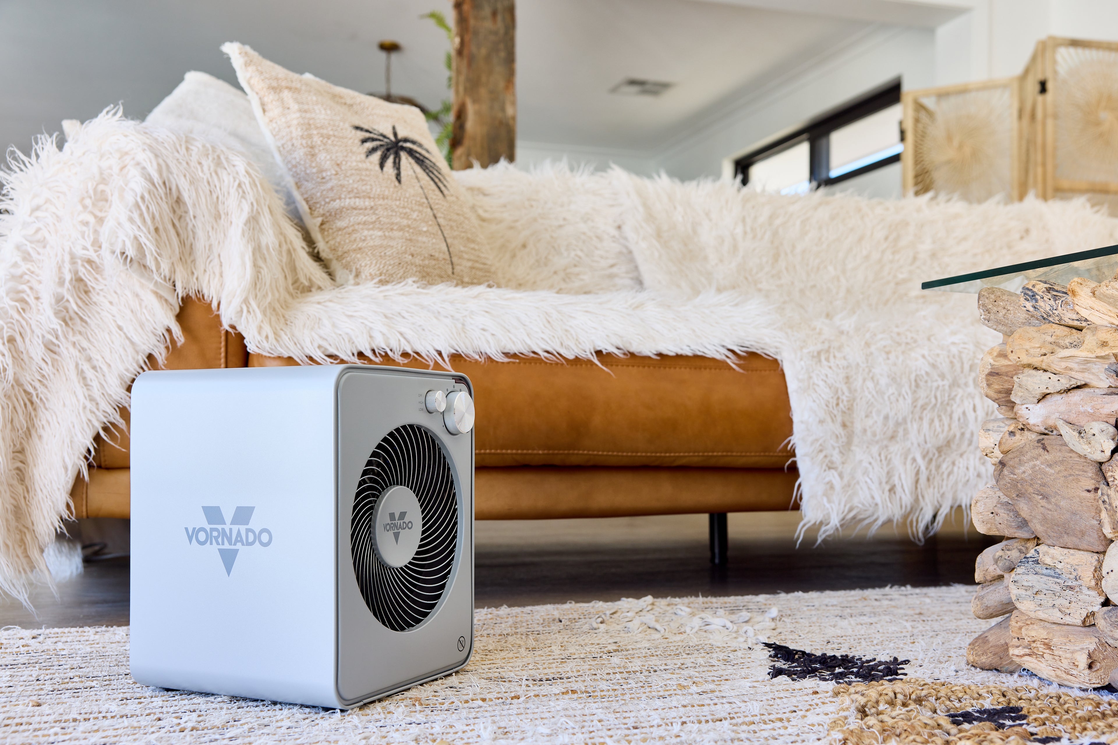 Portable powder-coated steel fan heater on a rug with a couch and decorative items in the background