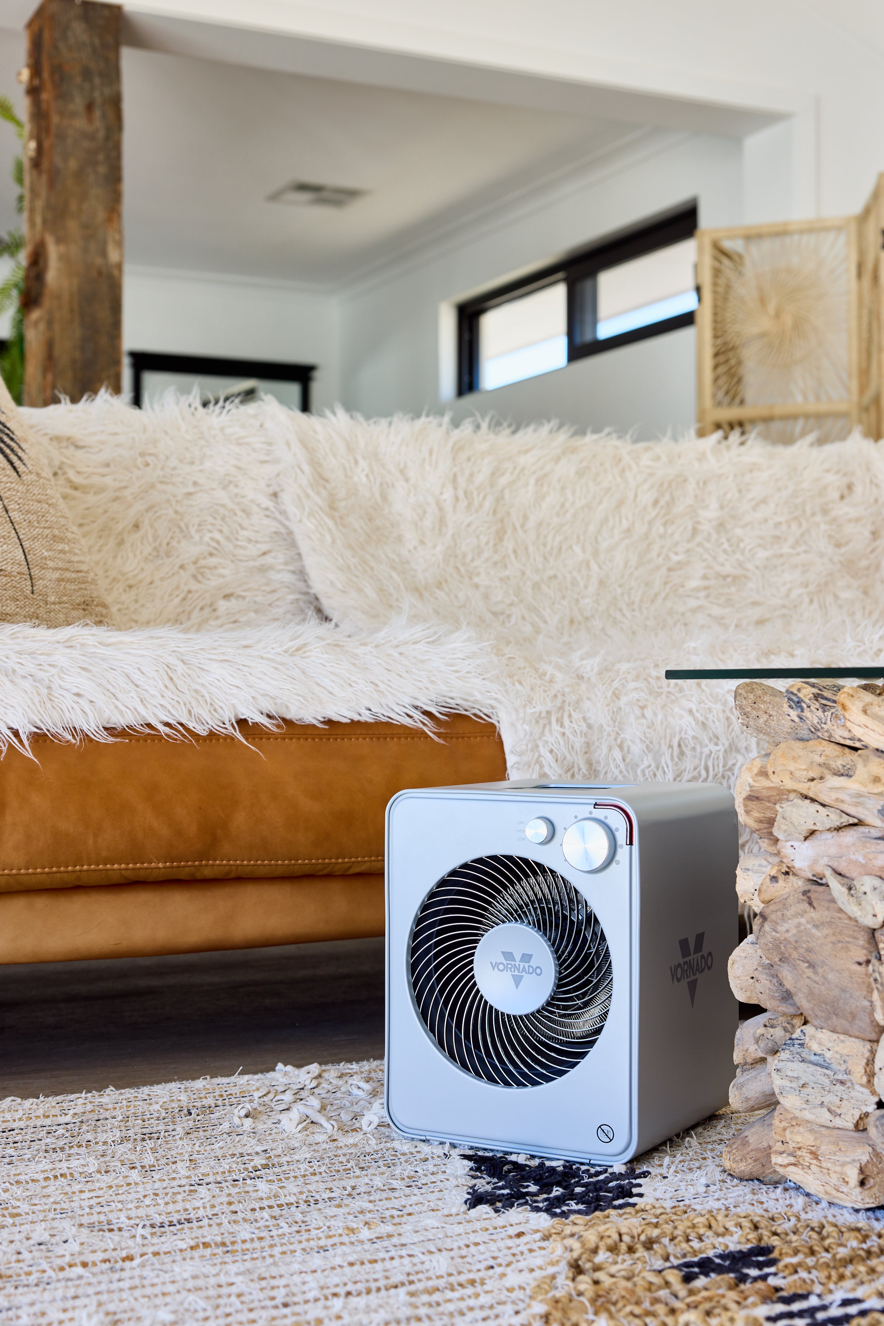 Portable Vornado fan Heater on a rug in a living room with a couch.
