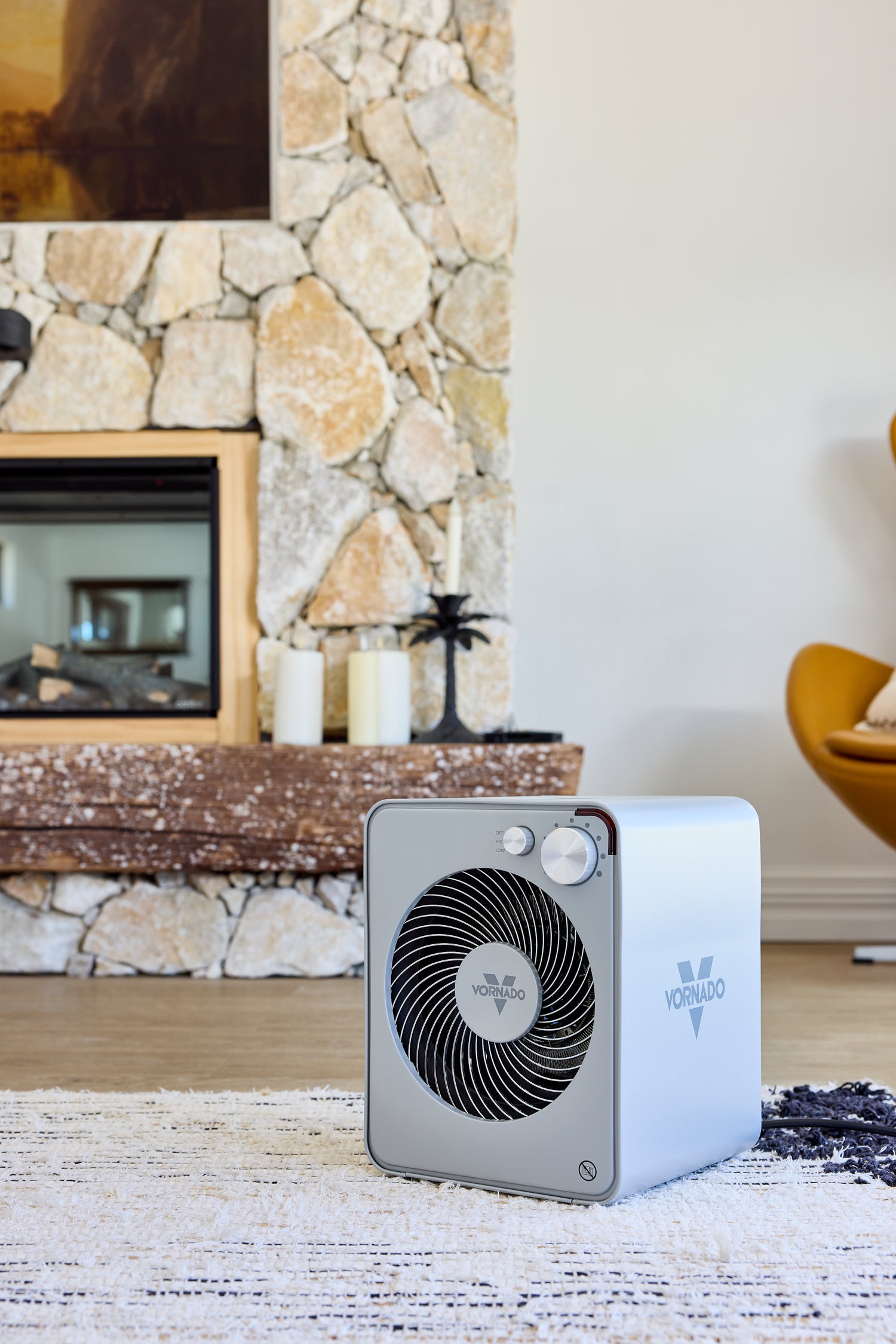 Portable fan heater on a wooden floor with a stone feature wall in the background