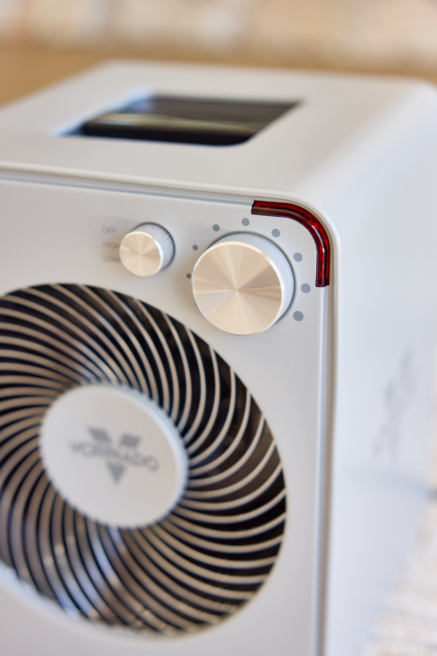 Close-up of a silver Vornado fan heater with control knobs and a brand logo.