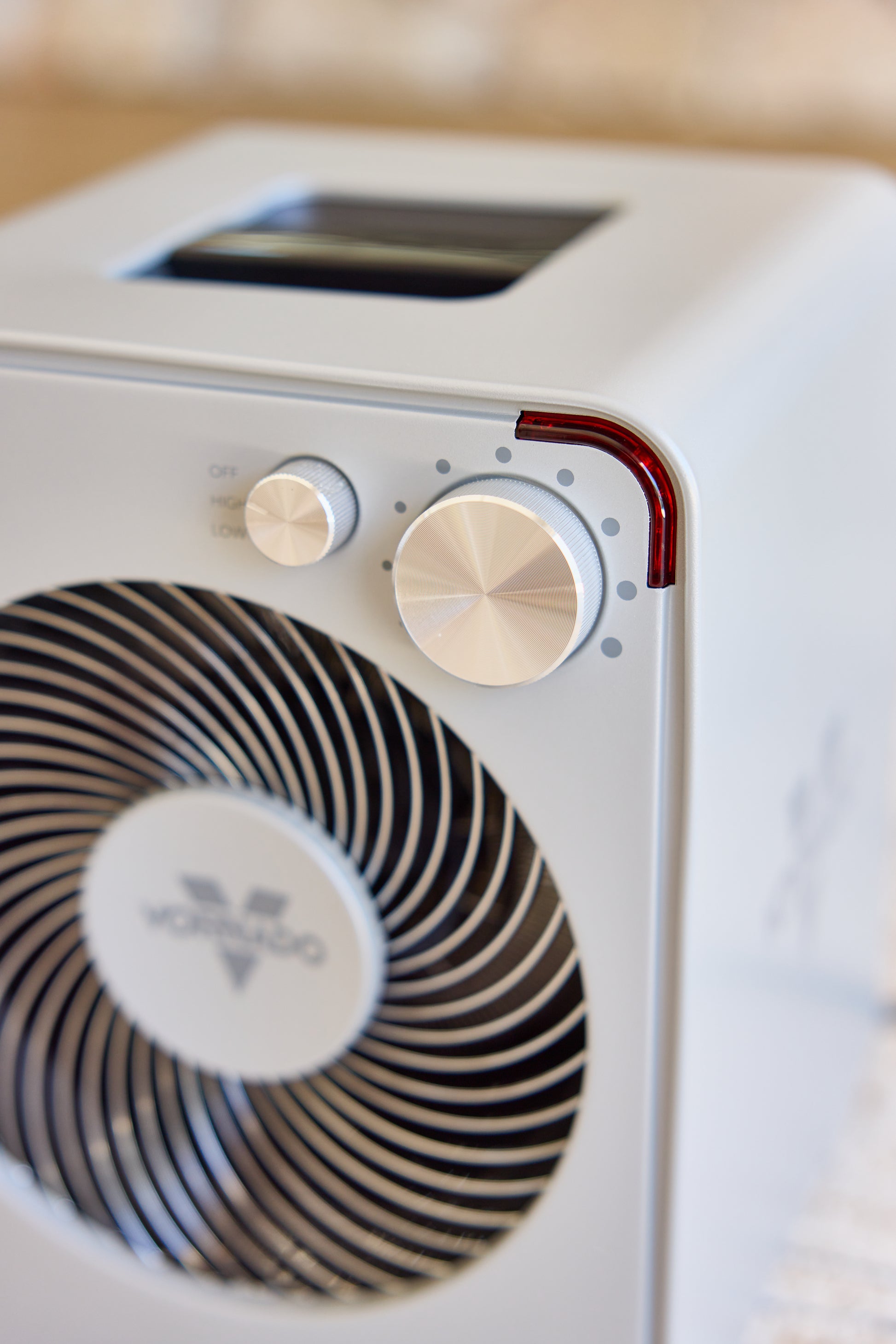 Close-up of a silver Vornado fan heater with control knobs and a brand logo.