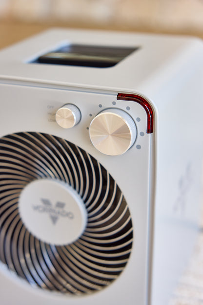 Close-up of a silver Vornado fan heater with control knobs and a brand logo.