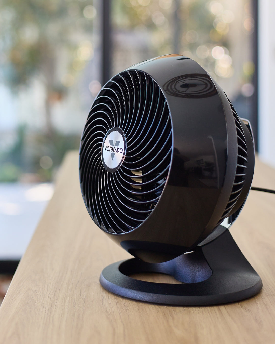 Black Vornado 560 Medium Air Circulator on a wooden kitchen benchtop with a blurred background