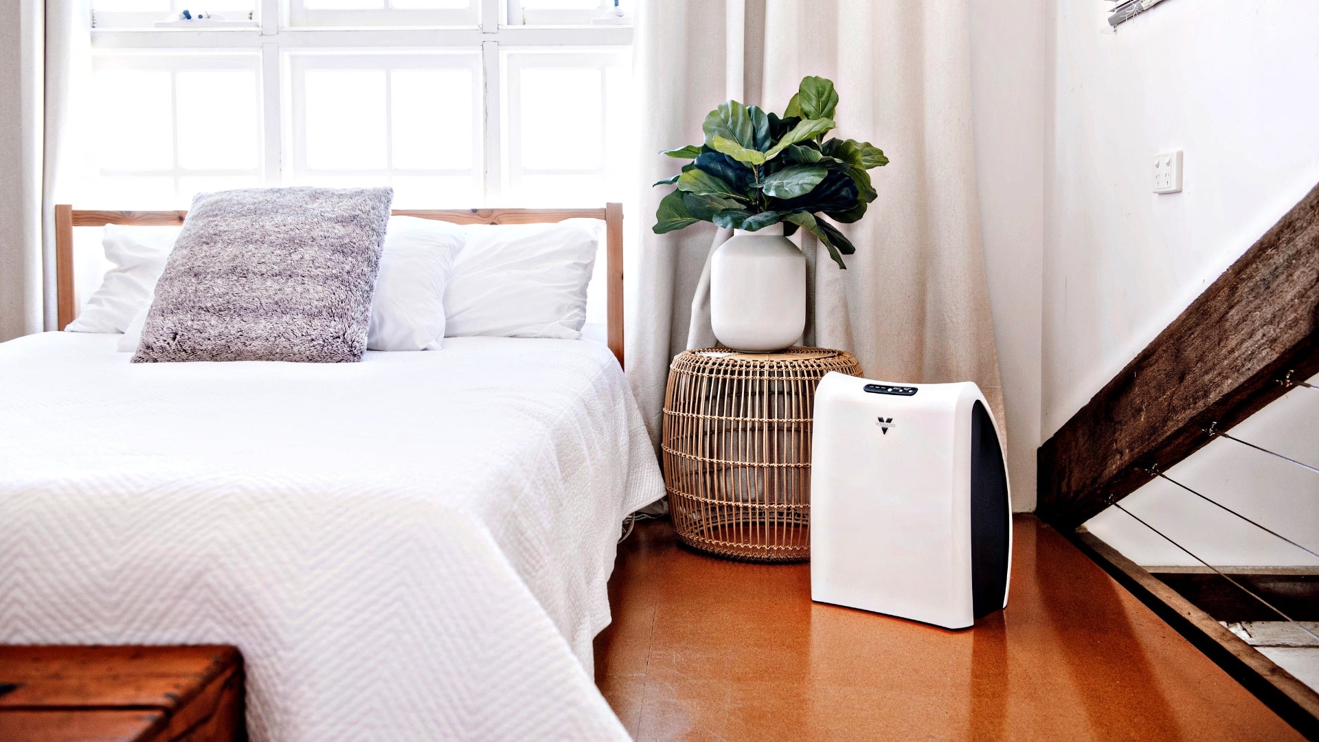 Vornado AC350 Air Purifier with True HEPA Filtration on a wooden floor next to a bed in a bedroom.