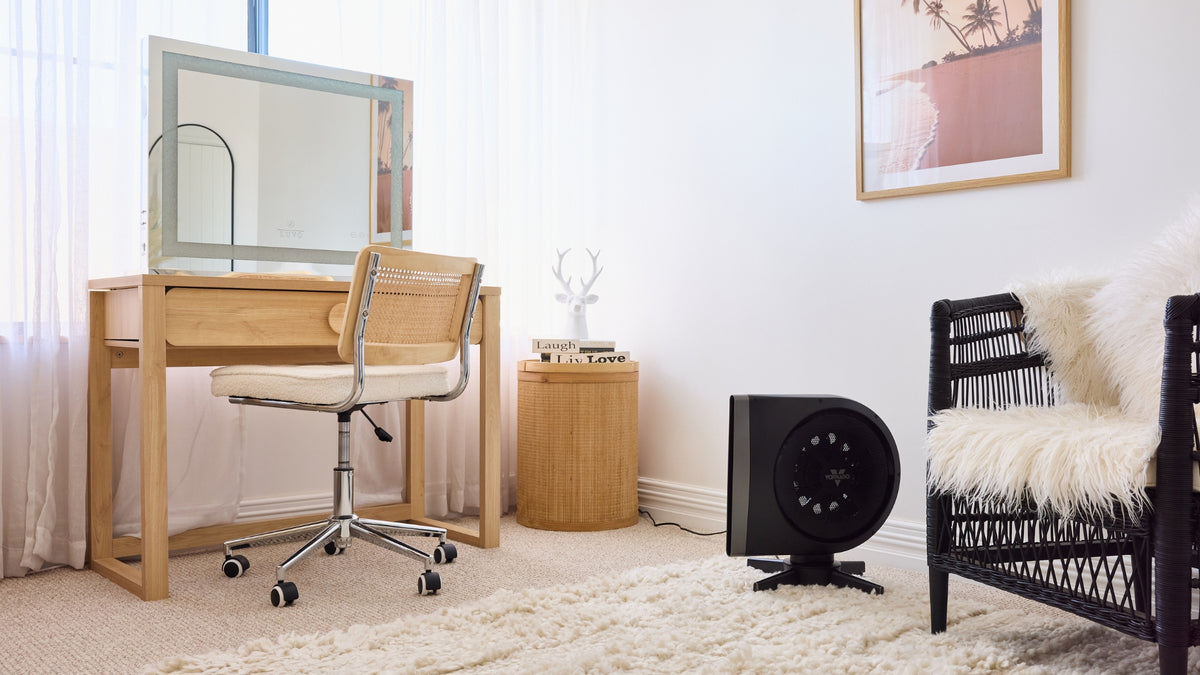 Vornado STRATA Fan on the floor in a dressing room with wooden desk, chair, and decorative items.