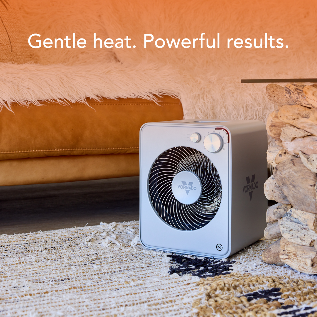 Portable space heater on a rug with text 'Gentle heat. Powerful results.' in a living room setting.